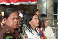 Mantan Bupati Minahasa Utara Vonnie Anneke Panambunan diapit petugas kejaksaan saat tiba di Bandara Sam Ratulangi Manado. (Foto/istimewa)