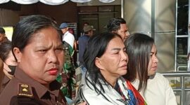 Mantan Bupati Minahasa Utara Vonnie Anneke Panambunan diapit petugas kejaksaan saat tiba di Bandara Sam Ratulangi Manado. (Foto/istimewa)