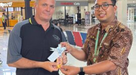 Salah satu penumpang pesawat yang mendapat sovenir cokelat dari petugas bandara (foto:istimewa)