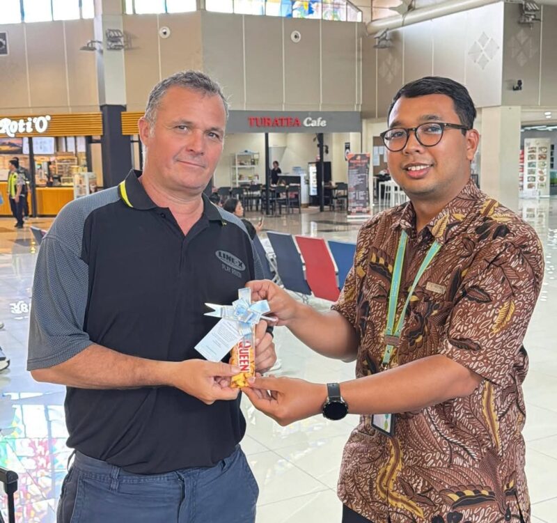 Salah satu penumpang pesawat yang mendapat sovenir cokelat dari petugas bandara (foto:istimewa)